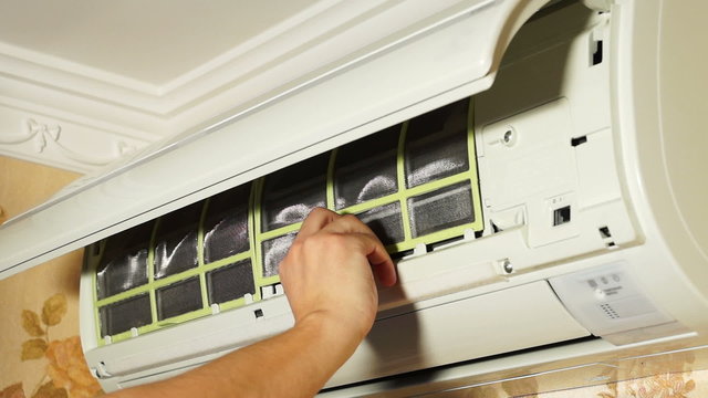 Man opens air conditioner and removes filters for cleaning
