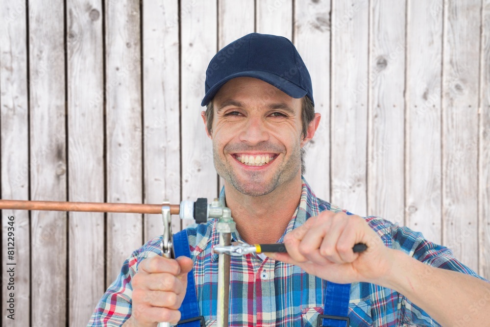 Poster Composite image of portrait of happy plumber fixing pipe
