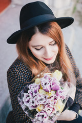 Pretty young woman wearing hat posing with flowers in her bag