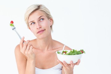 Thoughtful blonde eating salad
