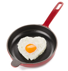 Heart shaped egg on cast iron cookware isolated