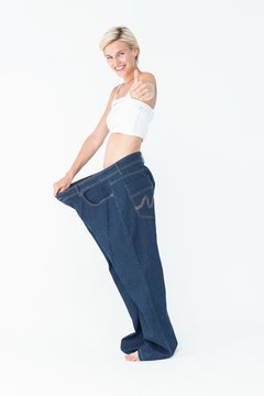 Blonde wearing too large pants with the thumb up