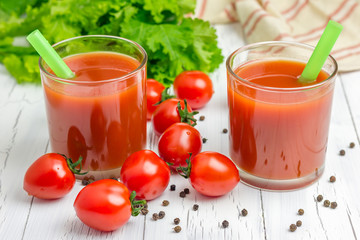 Refreshing glass of tomato juice with vegetables on background