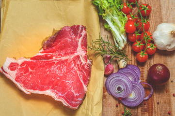 Meat with fresh vegetables, spices and meat cleaver on a wooden