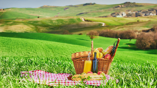 Tuscan picnic on the green spring grass with landscape in the ba