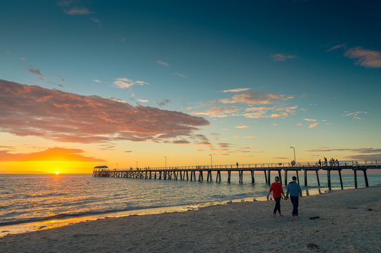 Young couple is walking along the beach at sunset