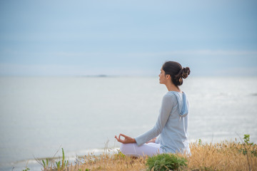 Naklejka na ściany i meble Woman meditating face to the ocean