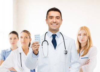 Fototapeta premium smiling male doctor in white coat with tablets