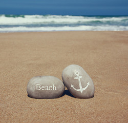 two stone pebbles with the word beach and anchor sign over sandy