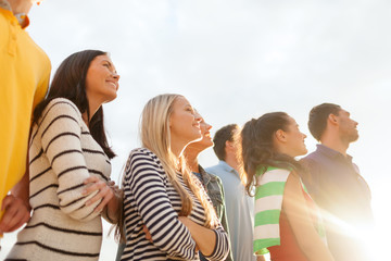 group of happy friends looking up on beach