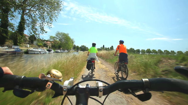 Retired couple cycling beside river on holidays