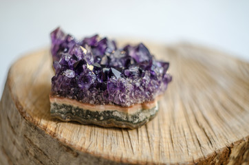 Raw amethyst rock with reflection on natural wood