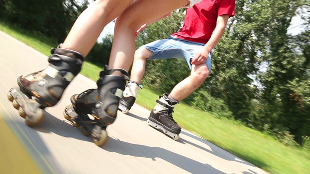 Happy young couple rollerblading on a wonderful sunny day in park, filming legs
