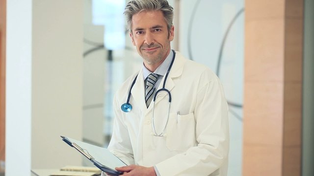 Mature doctor standing in hospital corridor