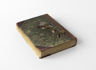 Old book and reading glasses on white background