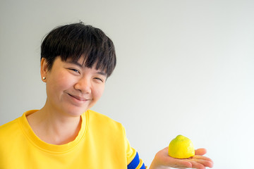 Portrait of young happy smiling woman with lemon, indoors