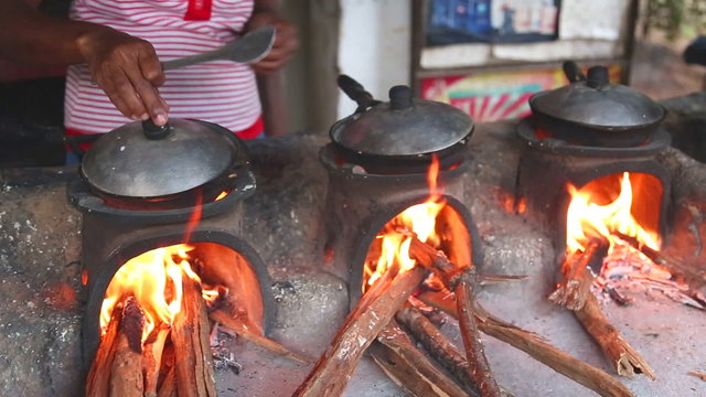 Woman cooking food on the side of the street. Street food is very common, tasty and inexpensive.