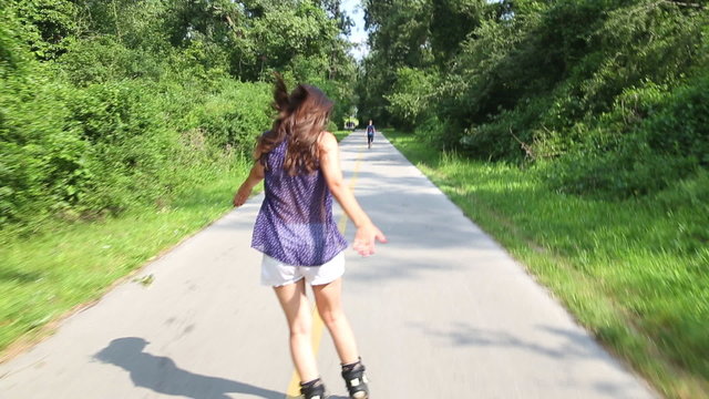 Young attractive woman rollerblading in park on a beautiful sunny day.