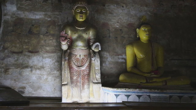 DAMBULLA, SRI LANKA - FEBRUARY 2014: Sitting Buddha and standing Buddha at the Golden Temple of Dambulla. The Golden Temple of Dambulla is a World Heritage Site in Sri Lanka.