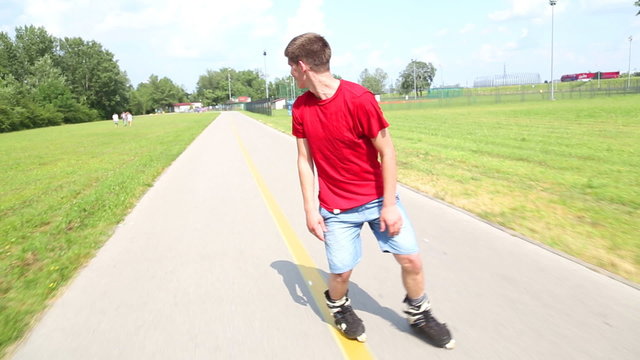 Young handsome man rollerblading in park on a beautiful day, playing around going backwards