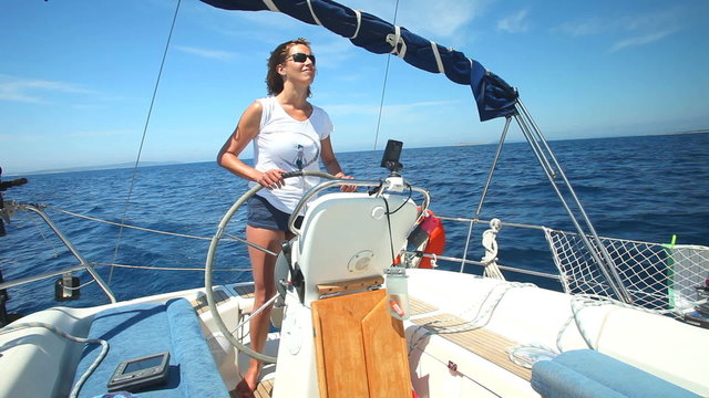 Woman at wheel steering sailboat on Adriatic sea in Croatia