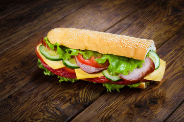 Sandwich with meat and vegetables on wood