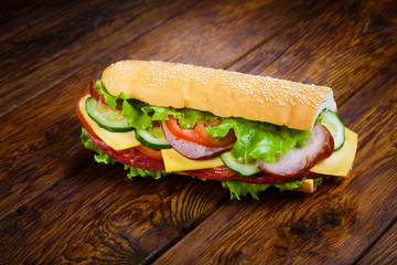 Sandwich with meat and vegetables on wood