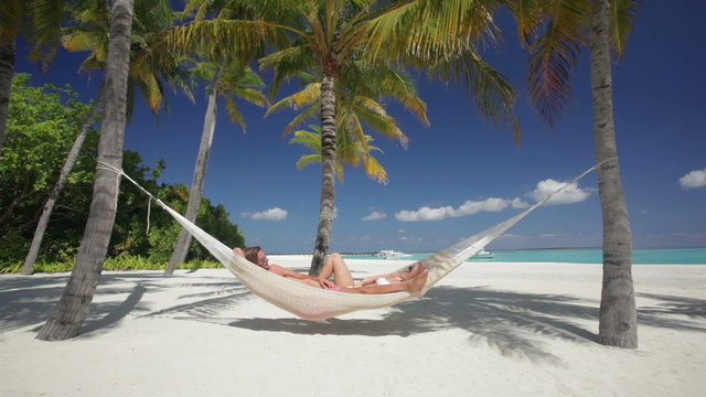 man and woman in hammock on tropical island