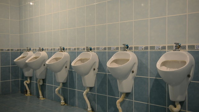 Interior of public men room with white urinals and tiles 