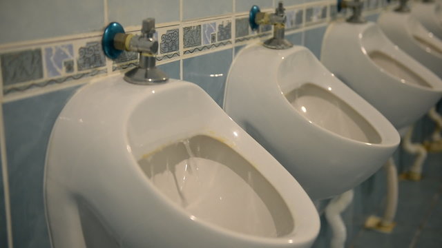 Interior of public men room with white urinals and tiles 