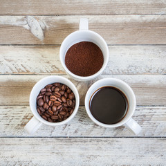 Three cups of coffee: beans, ground and brewed coffee