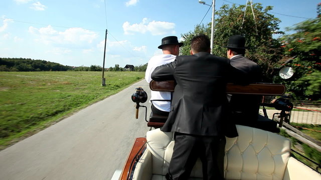 Men sitting on horse drawn carriage on road