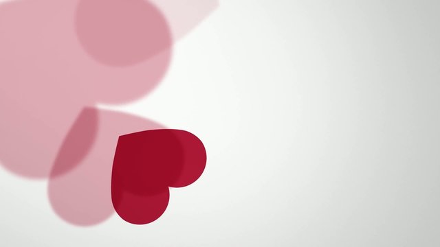 falling and rotating red hearts on light background
