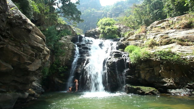 ELLA, SRI LANKA - MARCH 2014: Pan shot of people under the Ravana Falls in Ella. It currently ranks as one of the widest falls in the country.
