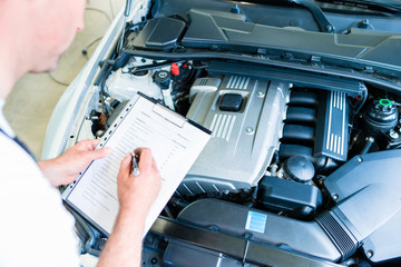 KFZ-Mechaniker mit Checkliste in Autowerkstatt