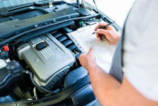 KFZ-Mechaniker mit Checkliste in Autowerkstatt