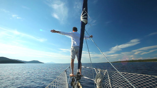 Man standing on the bow of sailing boat on Mediterranean sea.