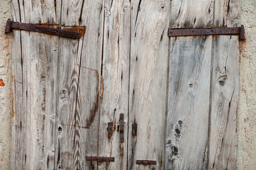 Vecchia porta di doghe di legno con cardini arrugginiti