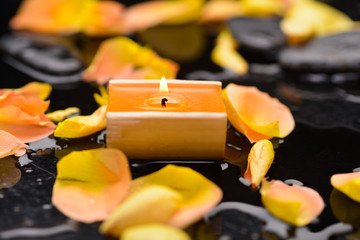 Set of orange rose petals with candle and therapy stones