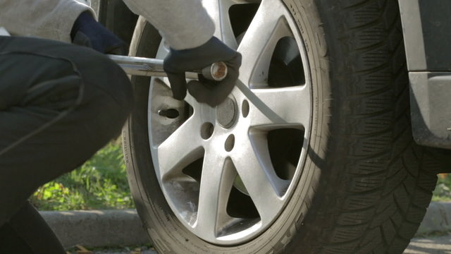 detail woman loosening screws of car tire
