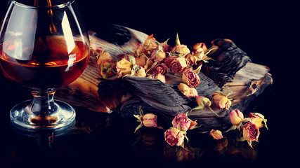 Rose petals on books and bottle of wine.