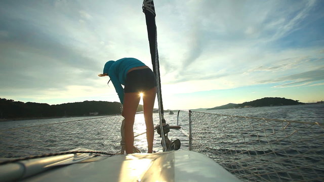 Woman preparing ropes on bow of sailboat on Adriatic sea in Croatia