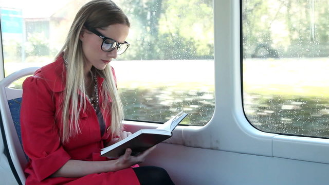 Beautiful woman riding tram, while reading book