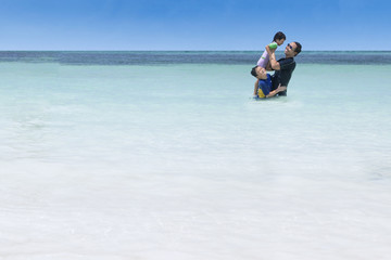 Fototapeta na wymiar Children and father having fun on beach