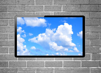 Blank screen LCD tv with blue sky hanging on a wall - obrazy, fototapety, plakaty