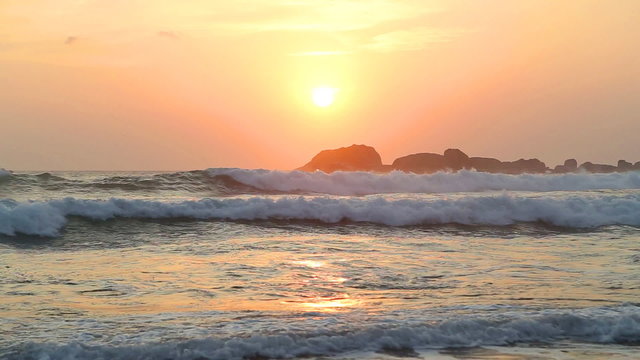 Ocean view in Hikkaduwa in sunset with waves splashing the beach.
