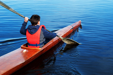 Fototapeta na wymiar The boy rowing in a kayak on the river