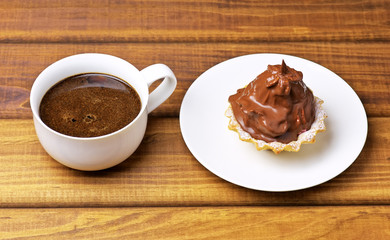 Cake on a plate and a cup of coffee on wooden table