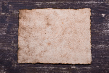 Old paper sheet at grunge wooden background with copy space