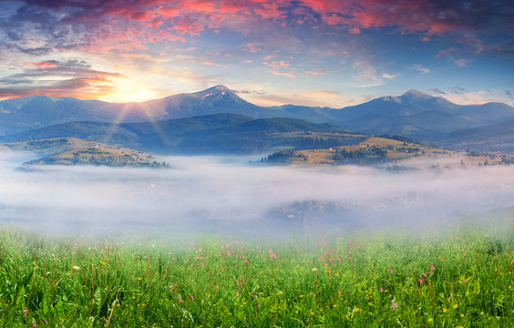 Colorful summer sunrise in a mountain village in the mist